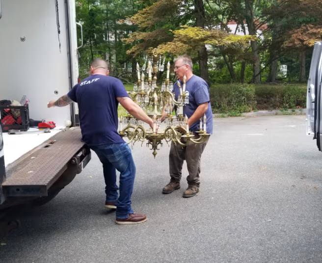 Men carrying an old chandelier to a loading truck